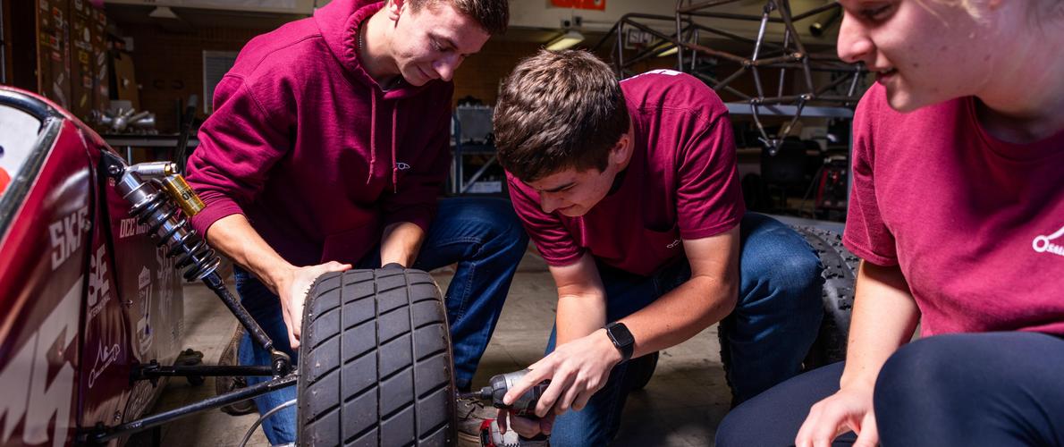 SIU Students work on changing the wheel on their baja buggie